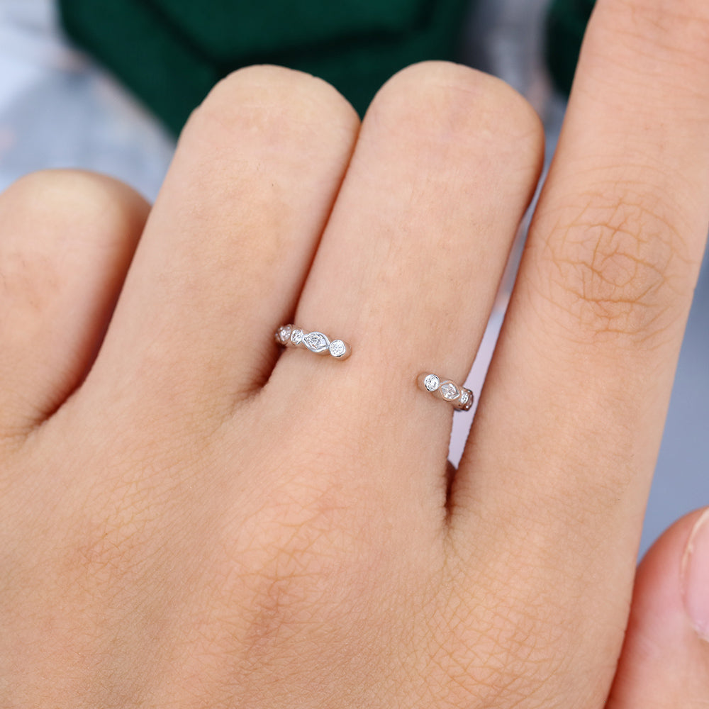 Marquise and round moissanite open bezel wedding band worn on a finger