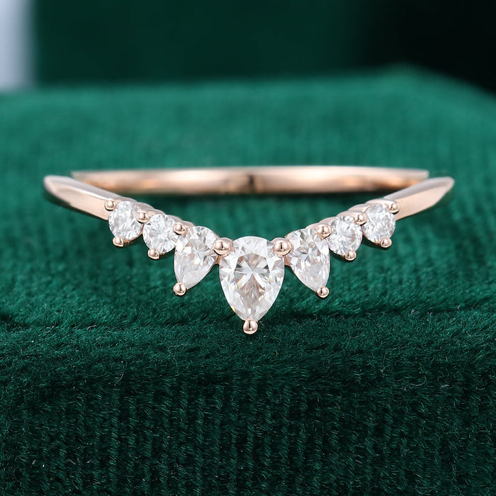 Front view of a rose gold curved wedding band with a center pear moissanite and graduated round and pear stones