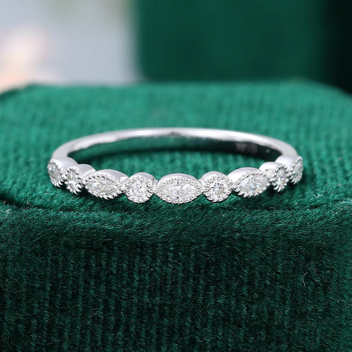 Front view of a vintage milgrain band with alternating marquise and round moissanite stones on green velvet