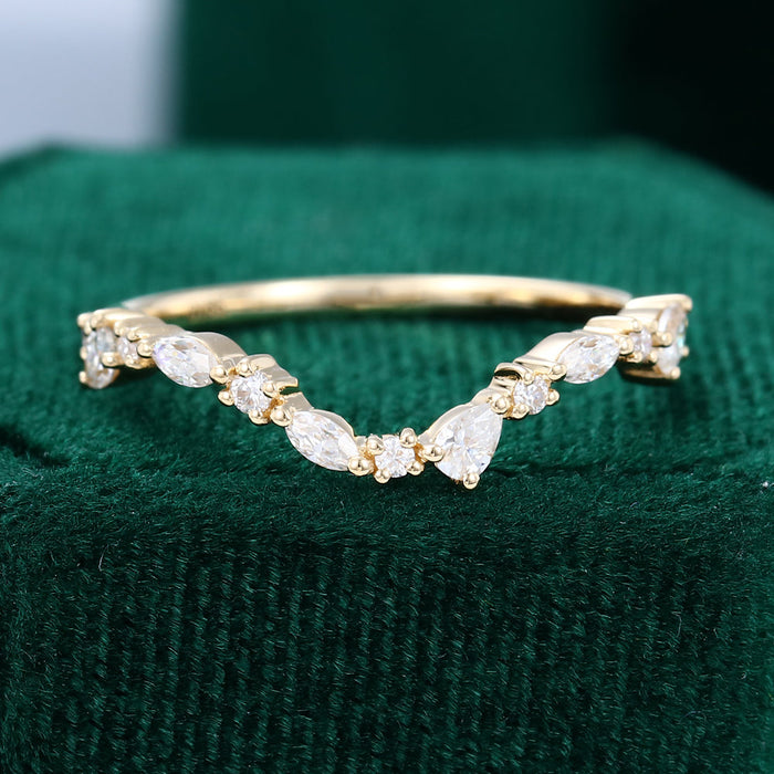 Front view of a curved yellow gold wedding band with marquise, pear and round moissanite stones