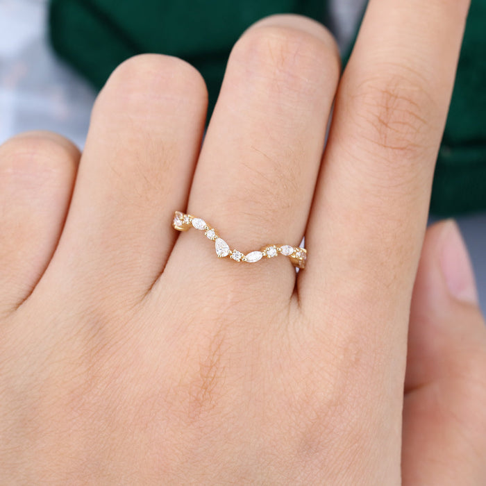 Marquise, pear and round moissanite curved wedding band in yellow gold worn on a finger