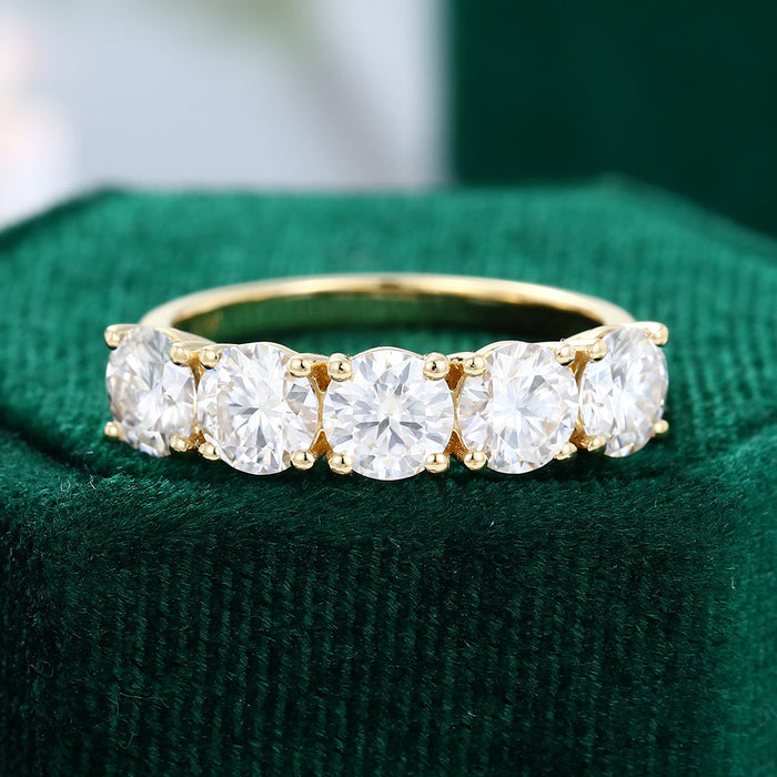 Front view of a round moissanite five stone wedding band in yellow gold