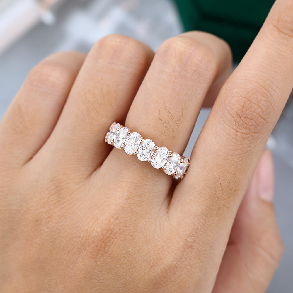 Oval moissanite bold full eternity wedding band in rose gold worn on the finger