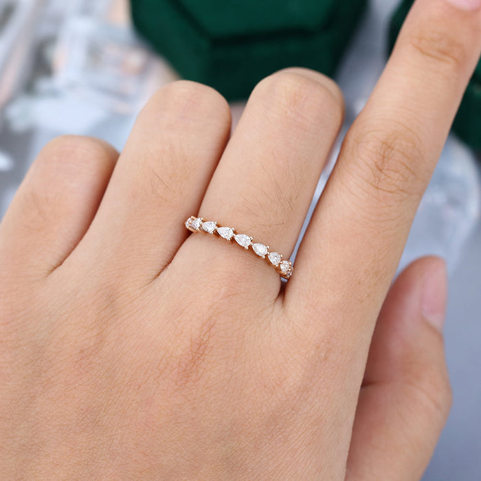 Pear moissanite half eternity wedding band in rose gold worn on the finger