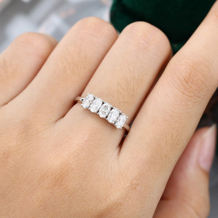 Oval moissanite five stone anniversary wedding band in white gold worn on the finger