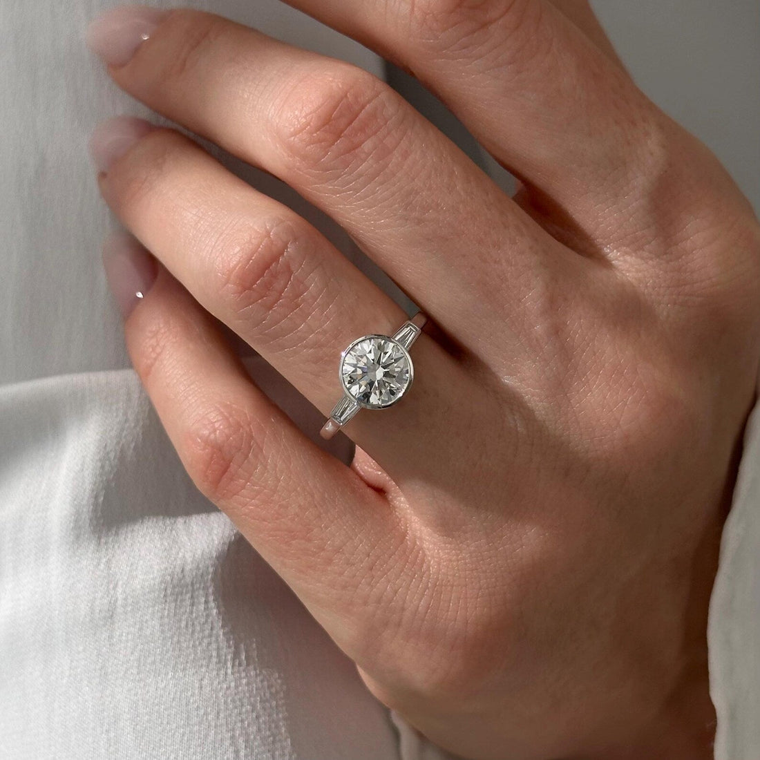 Bezel set round lab grown diamond three stone ring with tapered baguette side stones