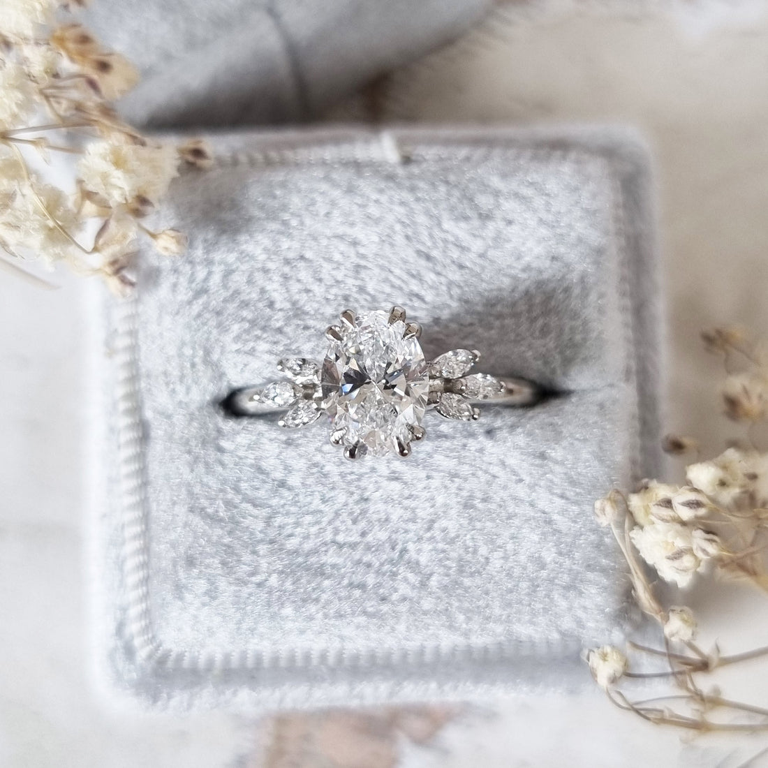 Oval cut lab grown diamond ring with marquise leaf shoulders in white metal