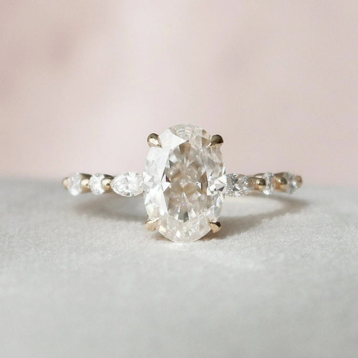 Oval cut moissanite cluster engagement ring with side stones in gold