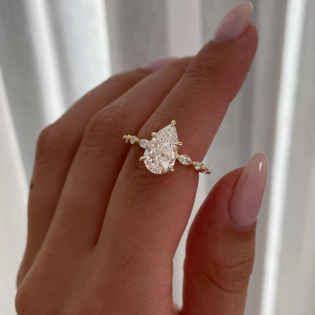Pear shaped moissanite engagement ring with diamond pave band in 14K gold