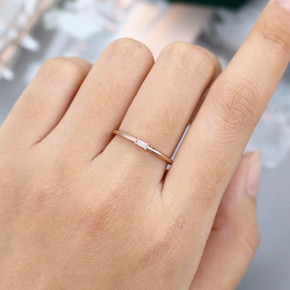 Baguette moissanite solitaire wedding band in rose gold worn on the finger
