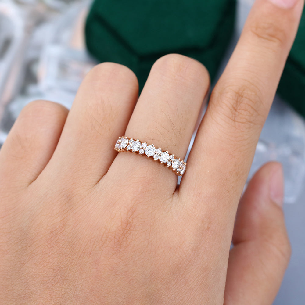 Round moissanite flower cluster half eternity wedding band in rose gold worn on a finger