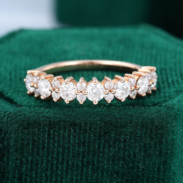 Front view of a rose gold band with large round stones and small flower style clusters on green velvet