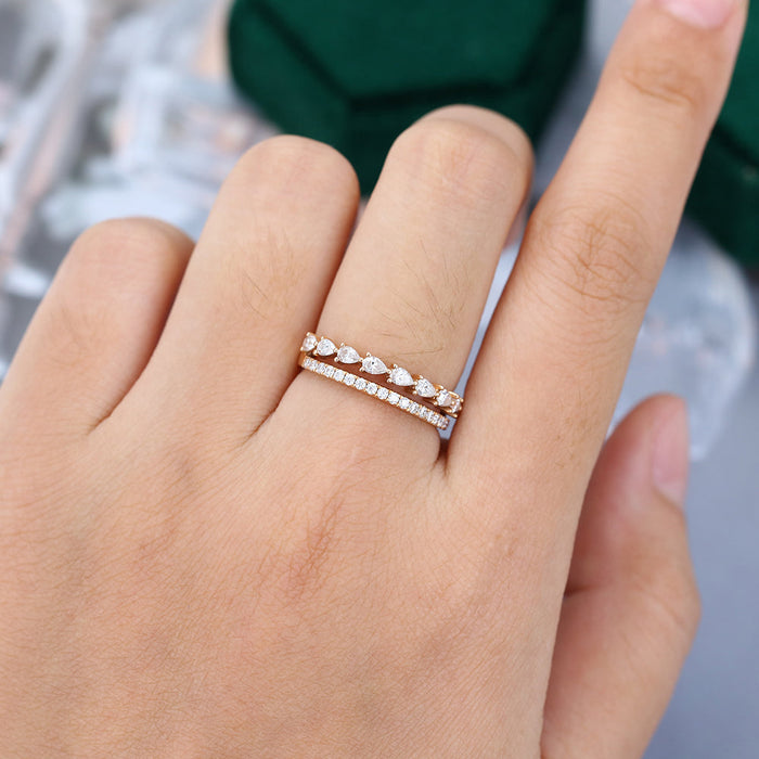 Pear and round moissanite double band wedding ring in yellow gold worn on a finger