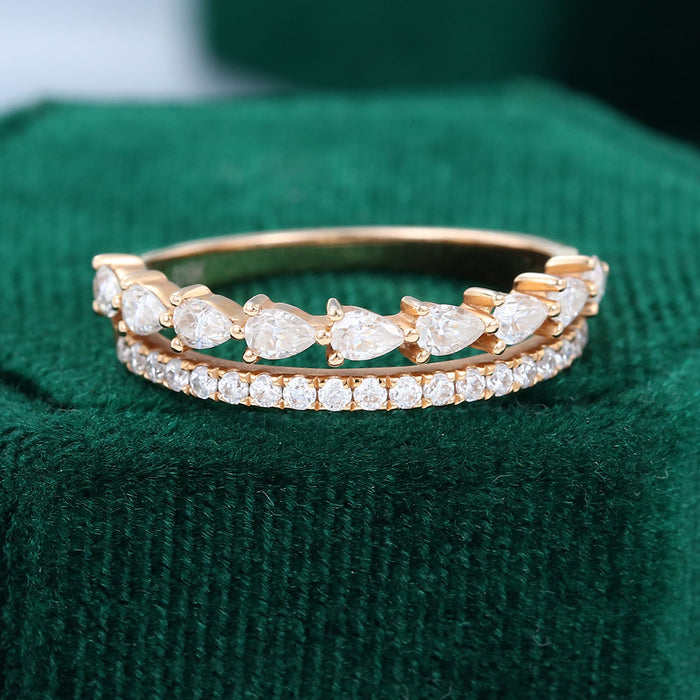 Front view of a yellow gold double band ring with a pear stone row above a round stone row on green velvet