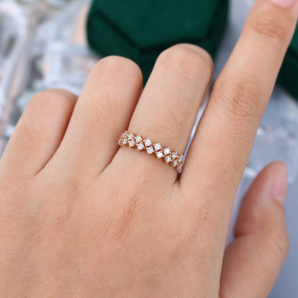 Round moissanite double row half eternity wedding band in rose gold worn on a finger