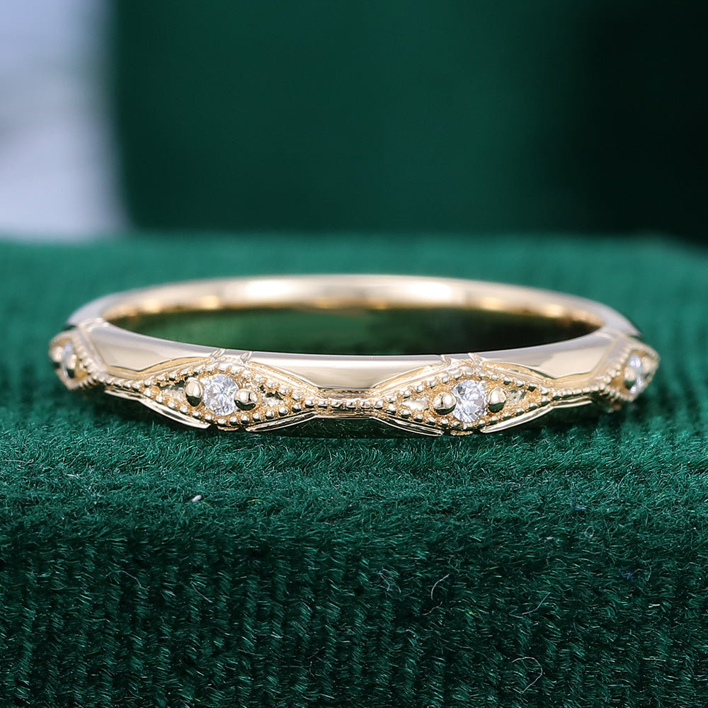 Round moissanite vintage milgrain station wedding band in yellow gold on green velvet
