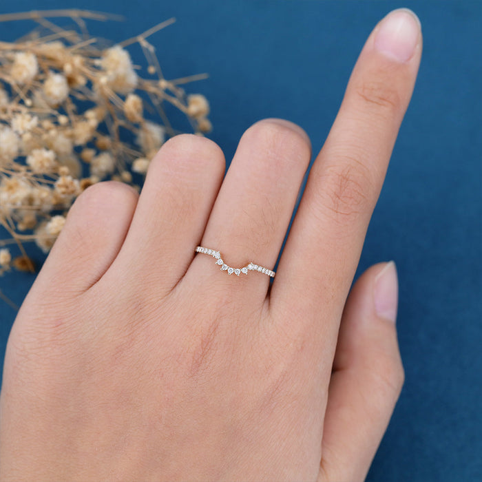 Round moissanite curved pave crown wedding band in yellow gold worn on a finger