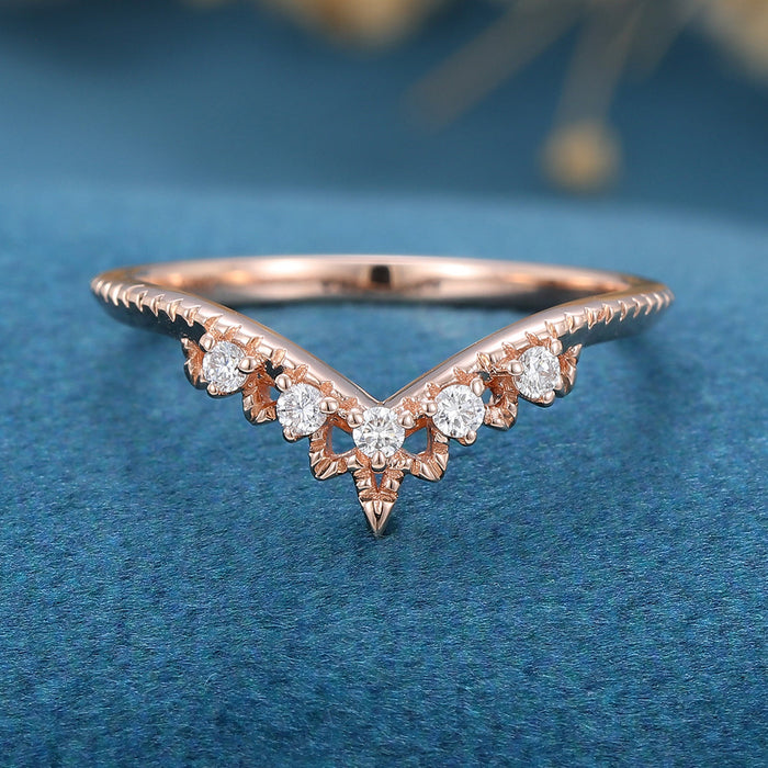 Front view of a round moissanite vintage curved wedding band with five stones and milgrain edging in rose gold