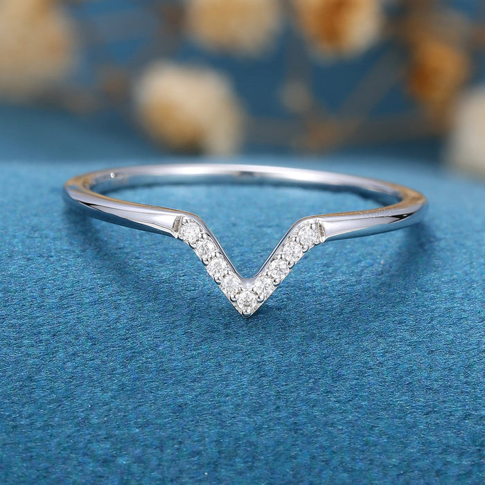 Front view of a V-shaped moissanite wedding band with small round stones along both arms in white gold