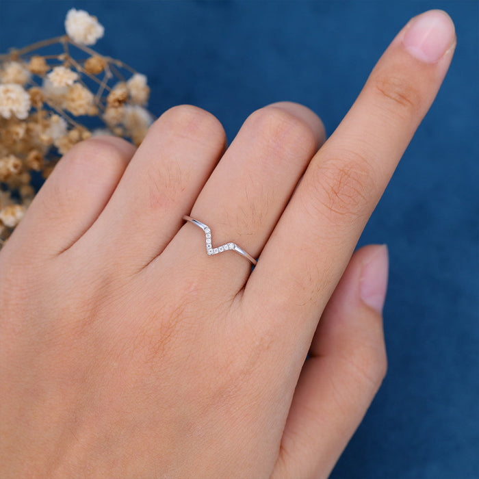 Round moissanite V-shaped curved wedding band in white gold worn on a finger