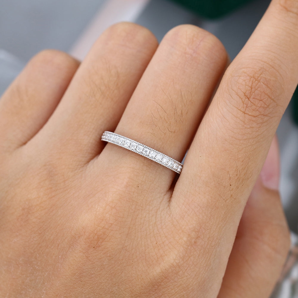 Round moissanite milgrain half eternity wedding band worn on a finger
