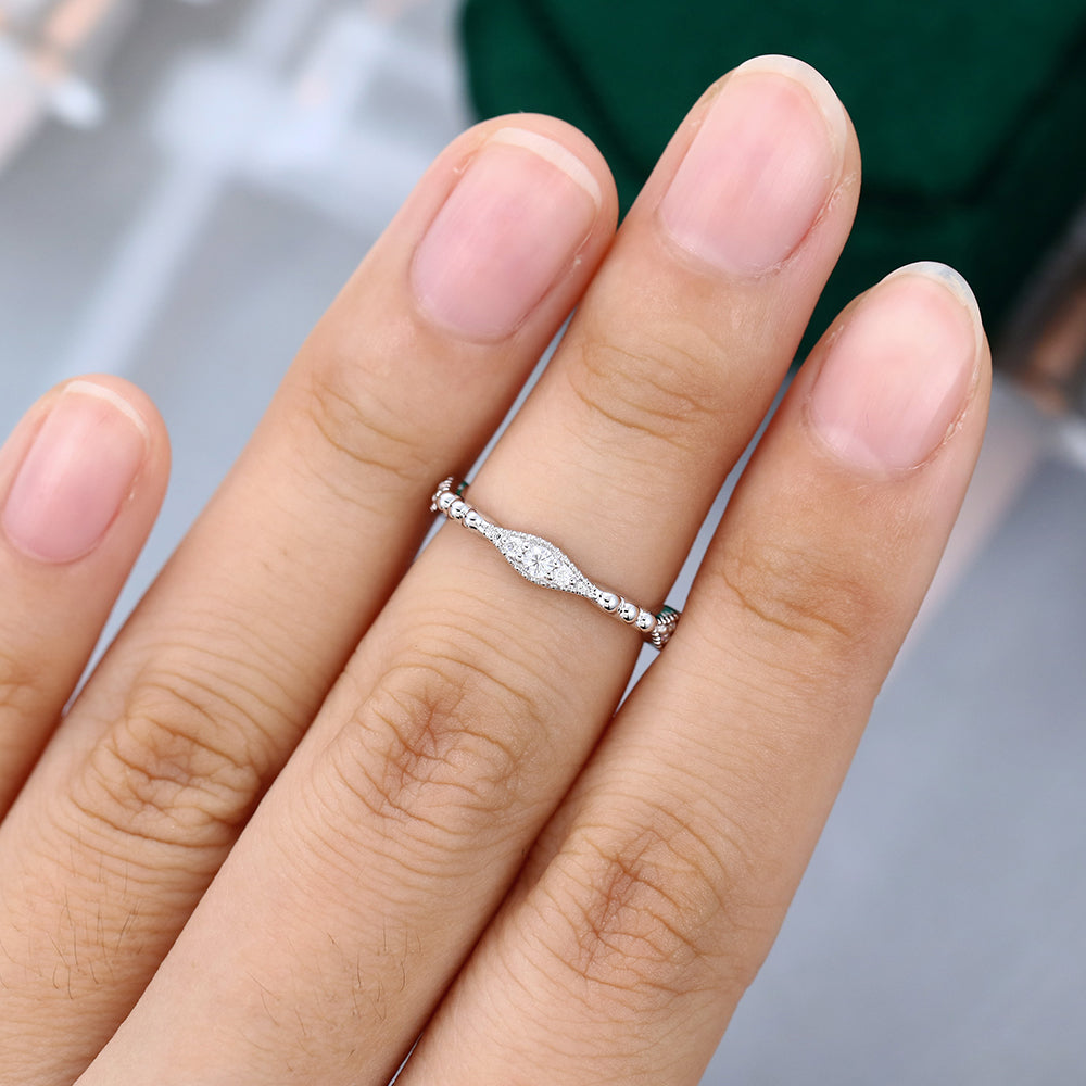 Round moissanite vintage beaded wedding band in white gold worn on the finger