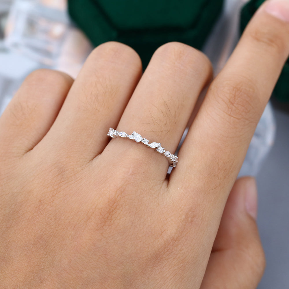 Round, pear and marquise moissanite cluster wedding band in white gold worn on the finger
