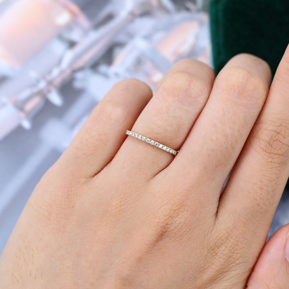 Round moissanite pave half eternity wedding band in yellow gold worn on the finger