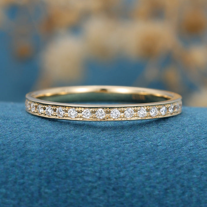 Front view of a channel set wedding band with a row of round moissanite stones and milgrain edges in yellow gold