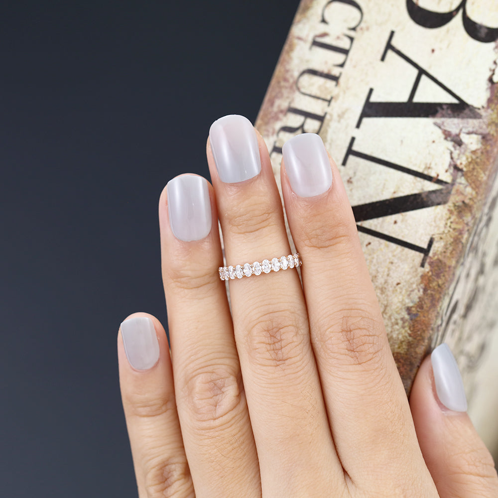 Oval moissanite half eternity wedding band in rose gold worn on the finger