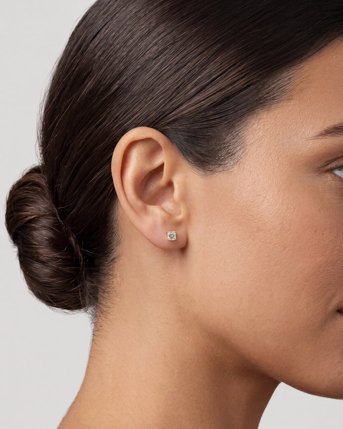Model wearing asscher everyday 4 prong solitaire lab grown diamond stud earrings, close up on the ear