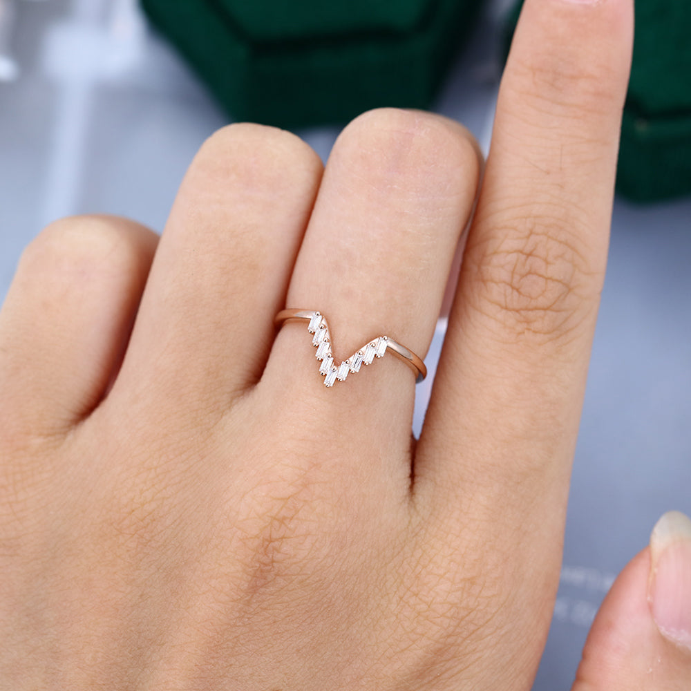 Baguette moissanite v-shaped curved wedding band, worn on the finger in rose gold