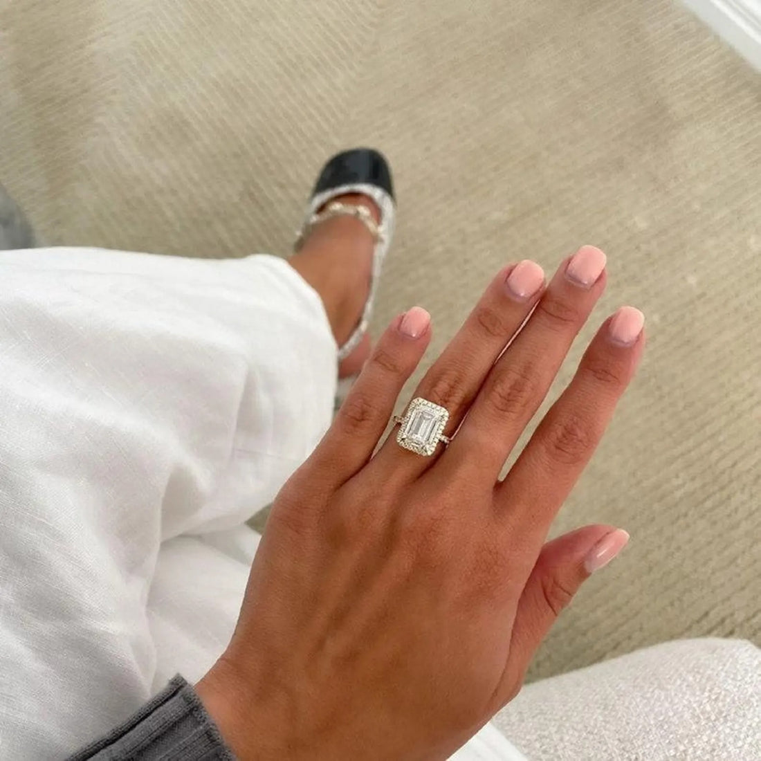 Emerald cut lab grown diamond halo engagement ring in yellow gold shown on the hand