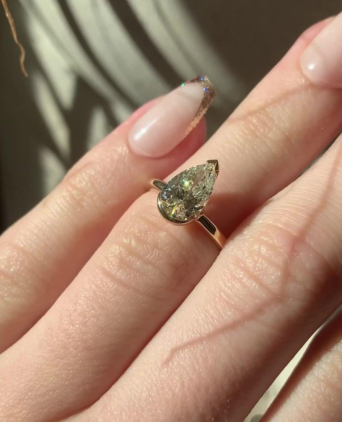 Elongated pear cut lab grown diamond engagement ring in a half bezel setting in yellow gold