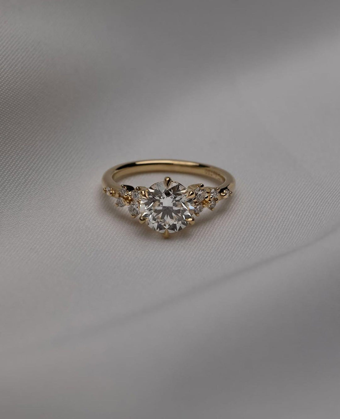 Round cut lab grown diamond engagement ring with scattered cluster accents in yellow gold