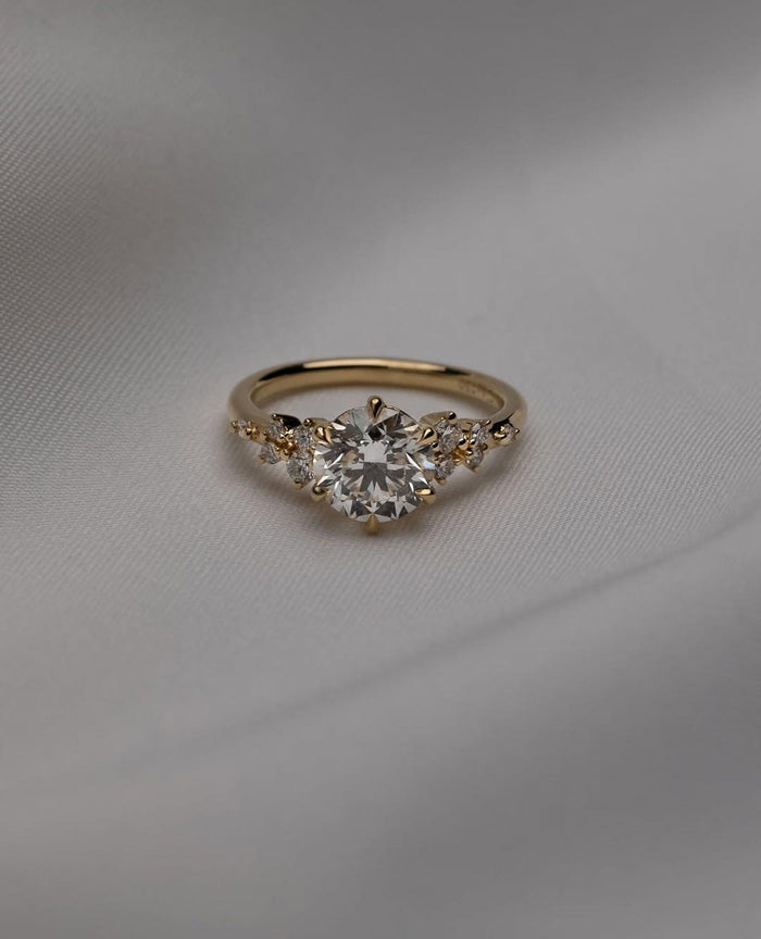 Round cut lab grown diamond engagement ring with scattered cluster accents in yellow gold