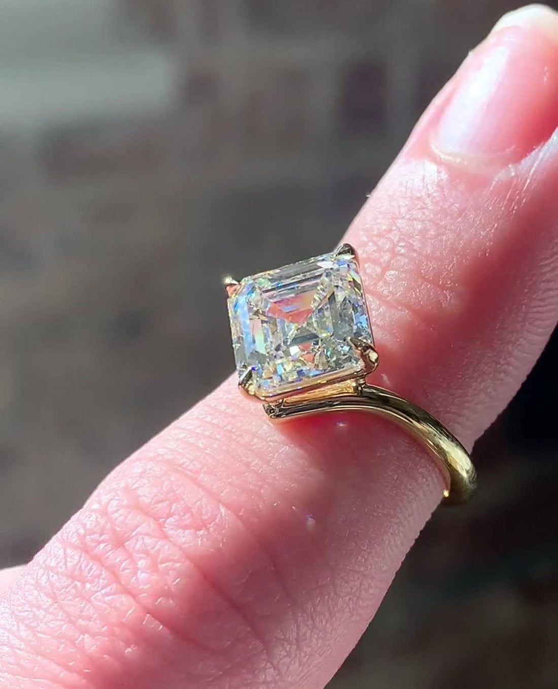 Asscher cut lab grown diamond solitaire engagement ring in yellow gold on the hand
