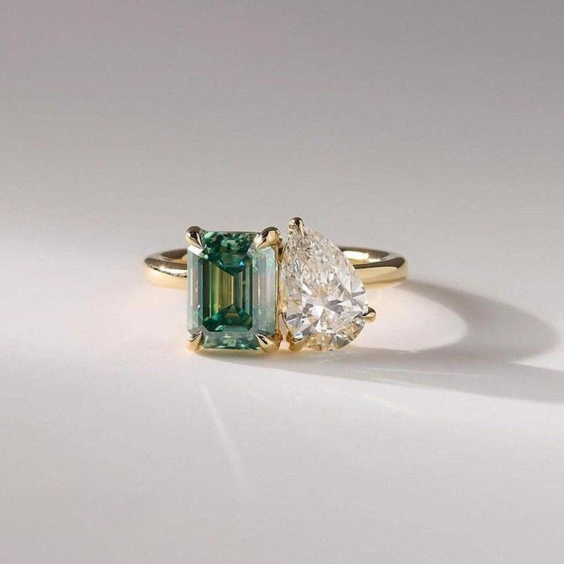 Toi et moi pear and green emerald cut ring on hand
