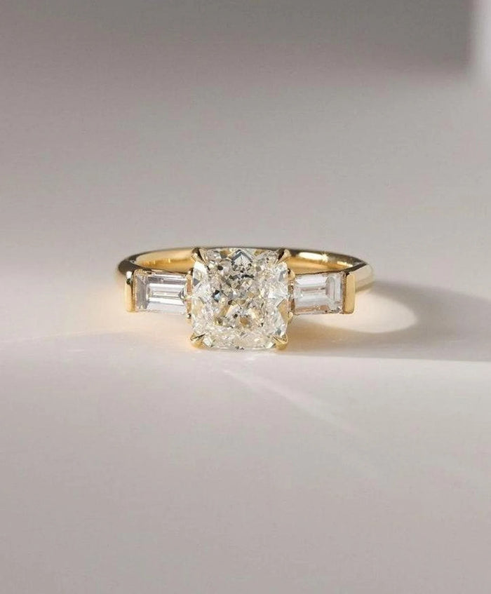 Cushion cut lab grown diamond three stone engagement ring with tapered baguettes in yellow gold