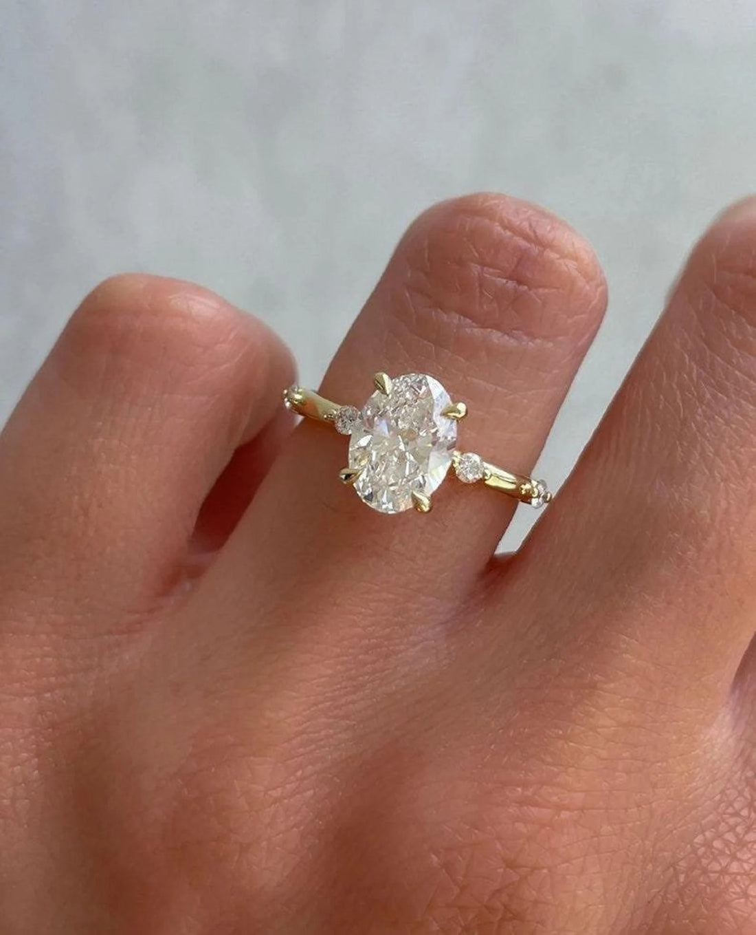 Oval cut lab grown diamond engagement ring with marquise and round accent band in yellow gold