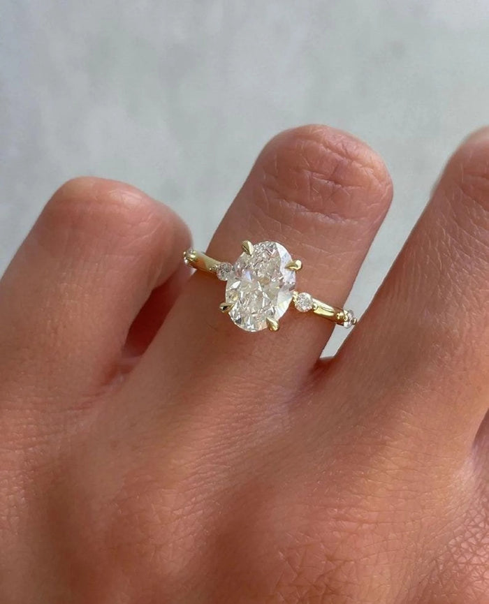 Oval cut lab grown diamond engagement ring with marquise and round accent band in yellow gold