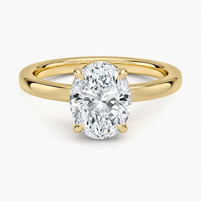 Oval cut lab grown diamond solitaire ring on a squared box basket in yellow gold, top view