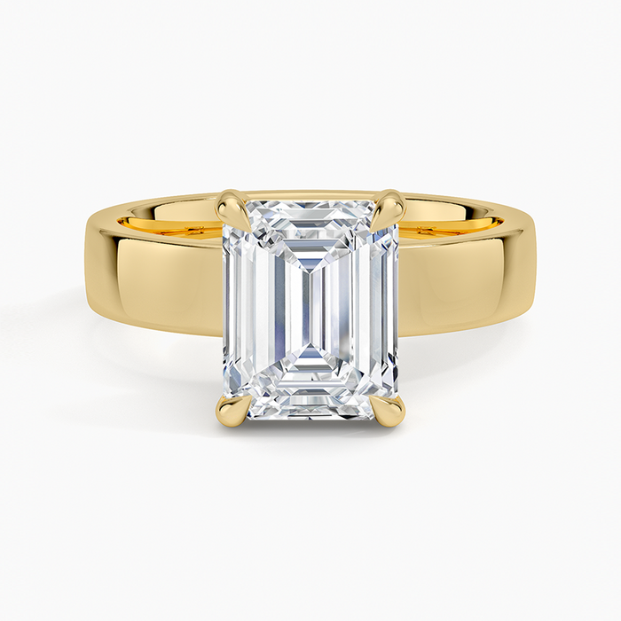 Emerald cut lab grown diamond ring in yellow gold set low into a wide polished band, top view