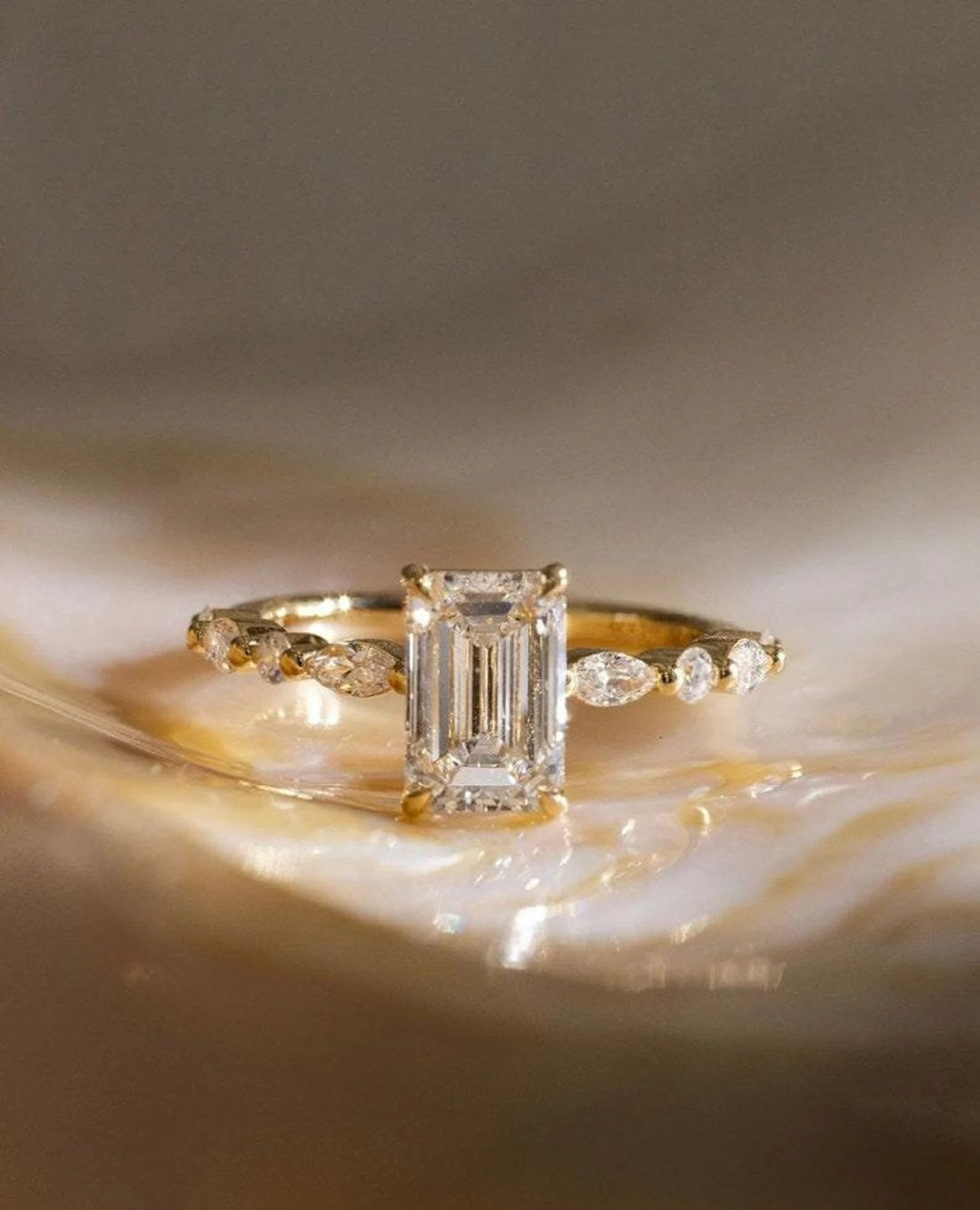 Emerald cut lab grown diamond engagement ring with marquise and round accent band in yellow gold