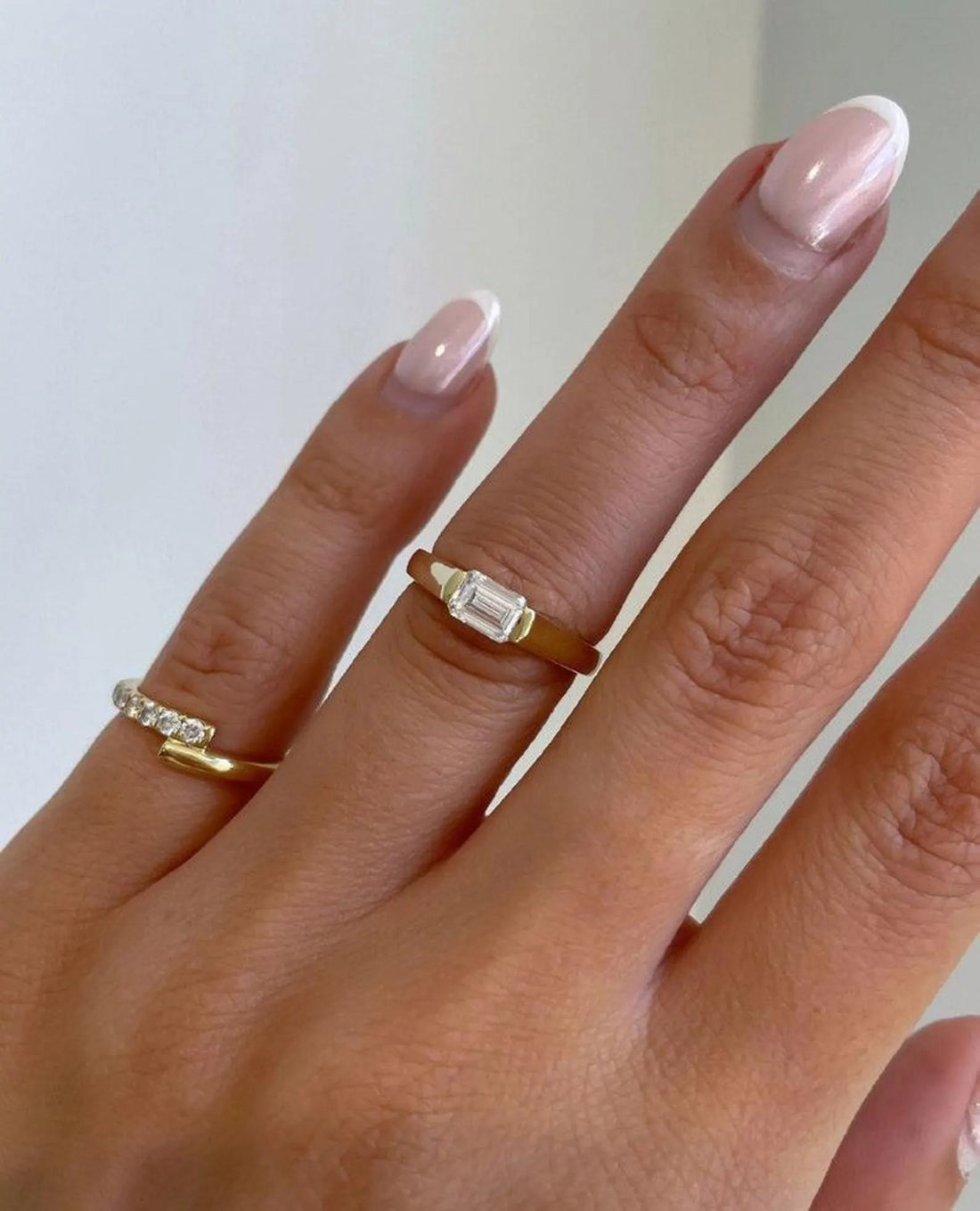East west emerald cut lab grown diamond ring set into a tapered yellow gold band