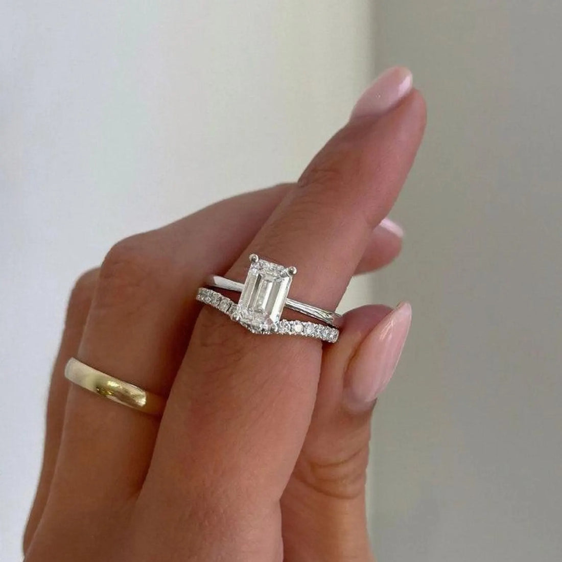 Emerald cut lab grown diamond engagement ring with pave band shown on the hand