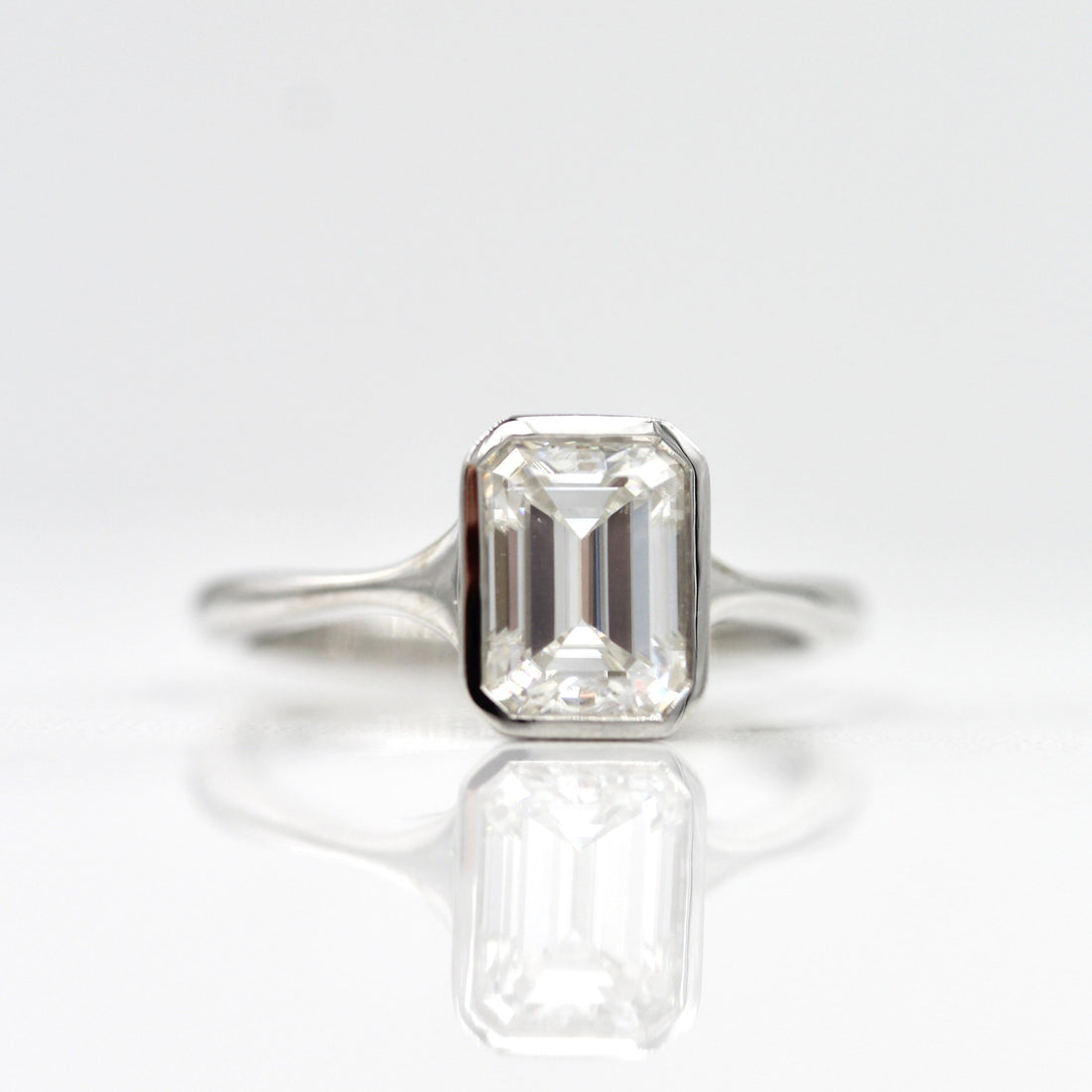 Emerald cut lab grown diamond bezel ring with tapered band