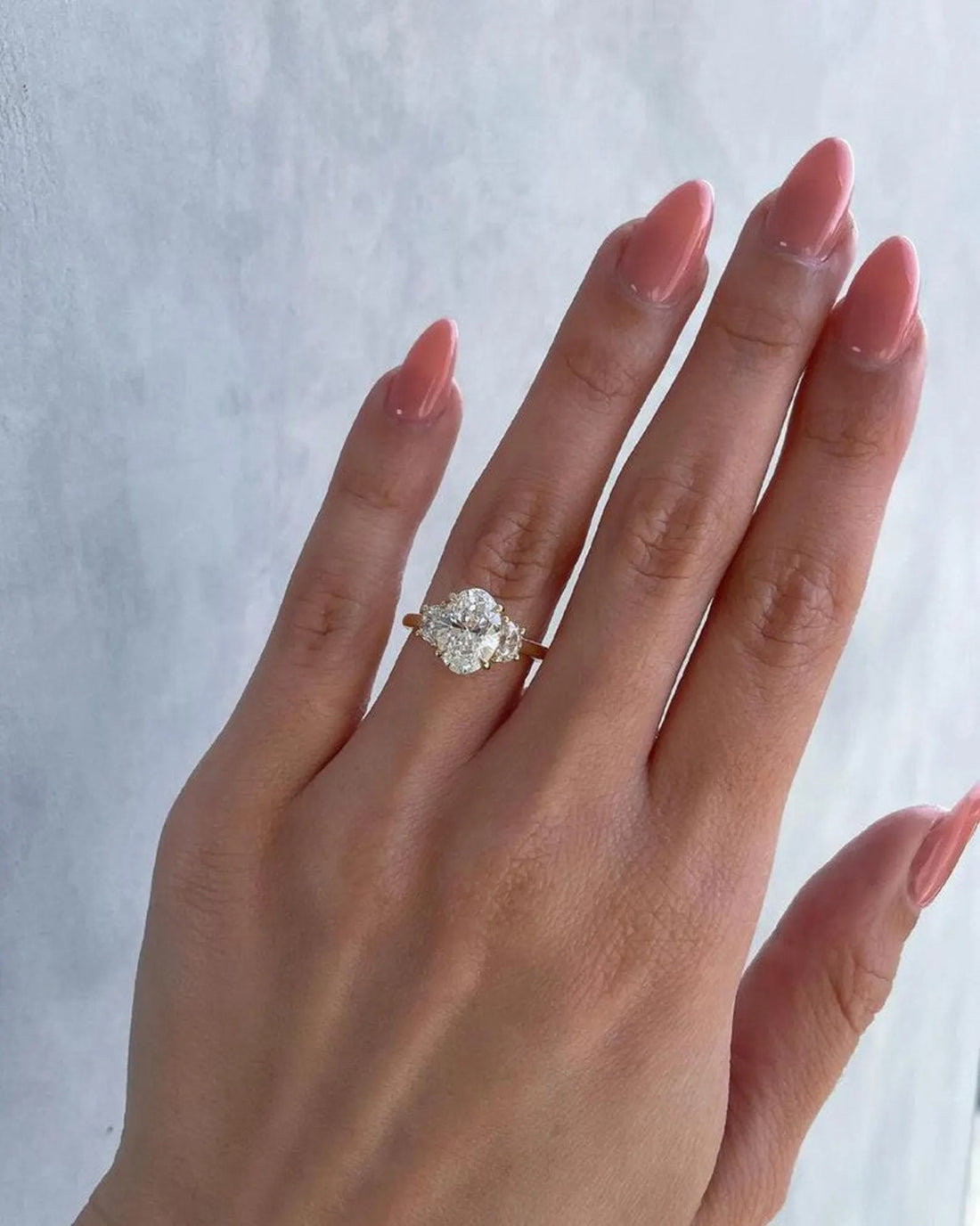 Three stone oval cut lab grown diamond engagement ring with oval side stones in yellow gold