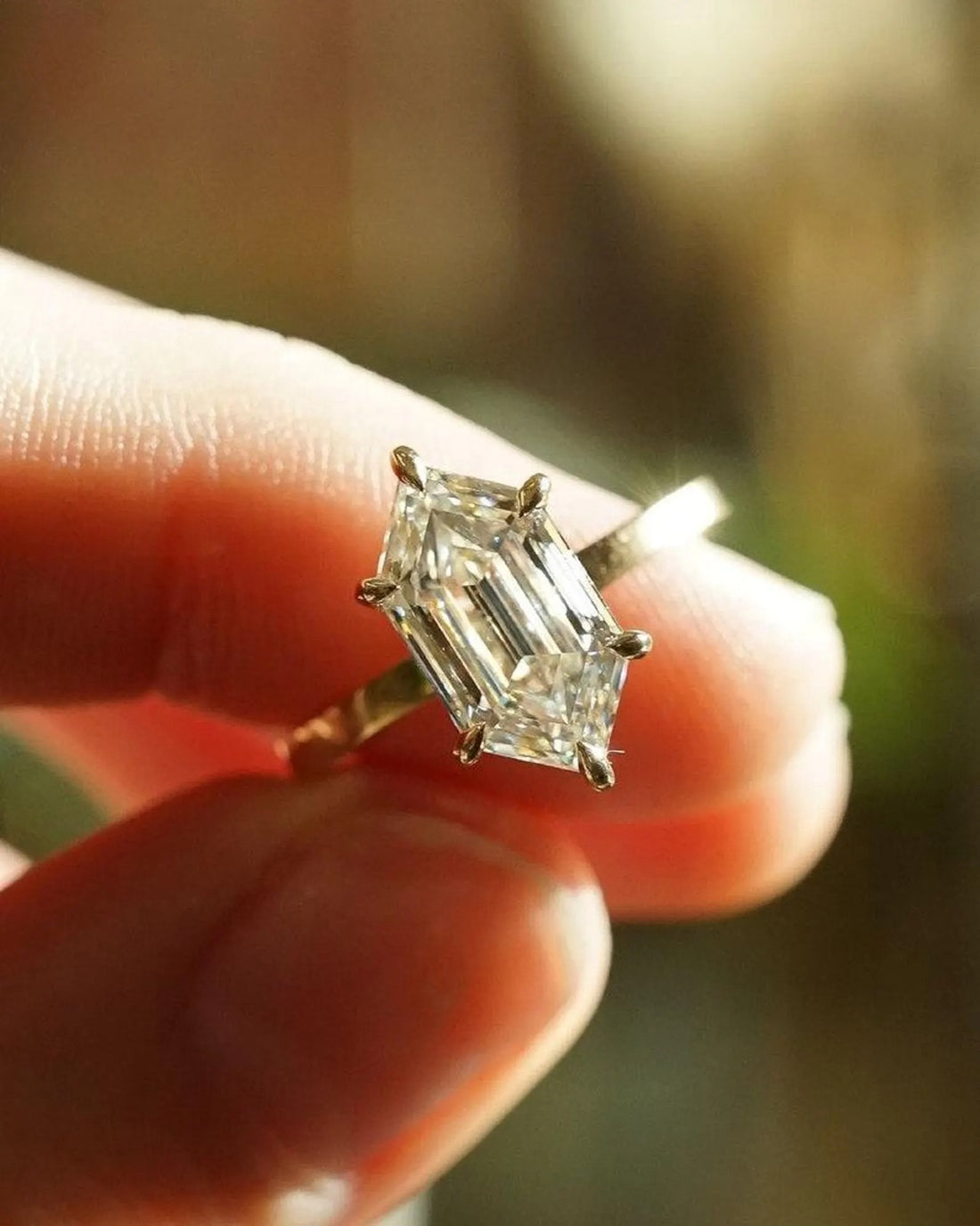 Hexagon cut lab grown diamond solitaire engagement ring held in the light