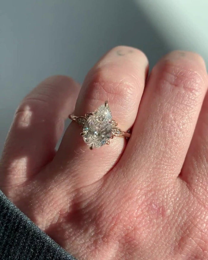 Pear cut diamond ring with marquise leaves worn on the hand, nature inspired setting